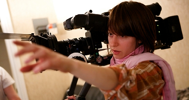 A young woman directs actors during filming.