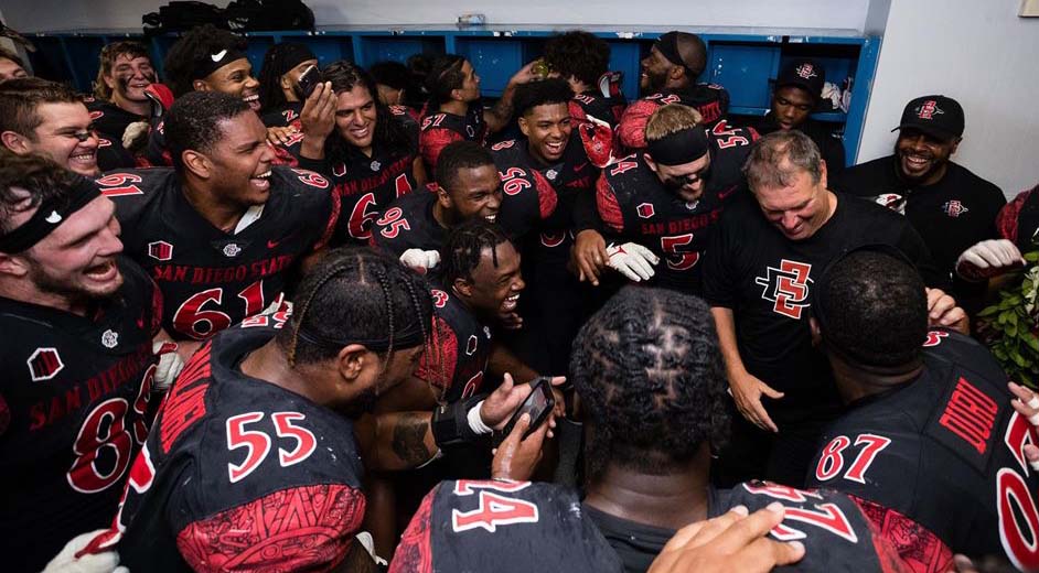 The Aztecs football team assembled in their locker room with Head Coach Brady Hoke (right) following a victory Friday over Boise State.