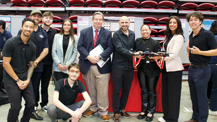 SDSU engineering students and their professor pose for a photograph during Senior Design Day at Viejas Arena.