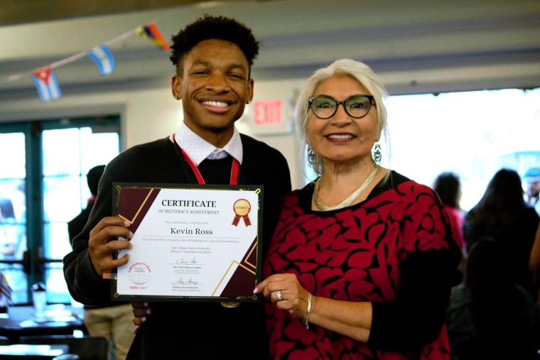 SDSU student Kevin Ross displays his University Seal of Biliteracy and Cultural Competence certificate with Cristina Alfaro, Associate Vice President of International Affairs 