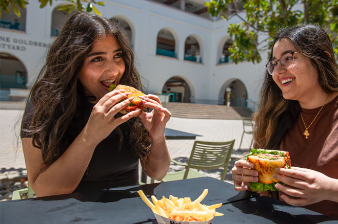 Two students eating hamburgers in the Union courtyard.