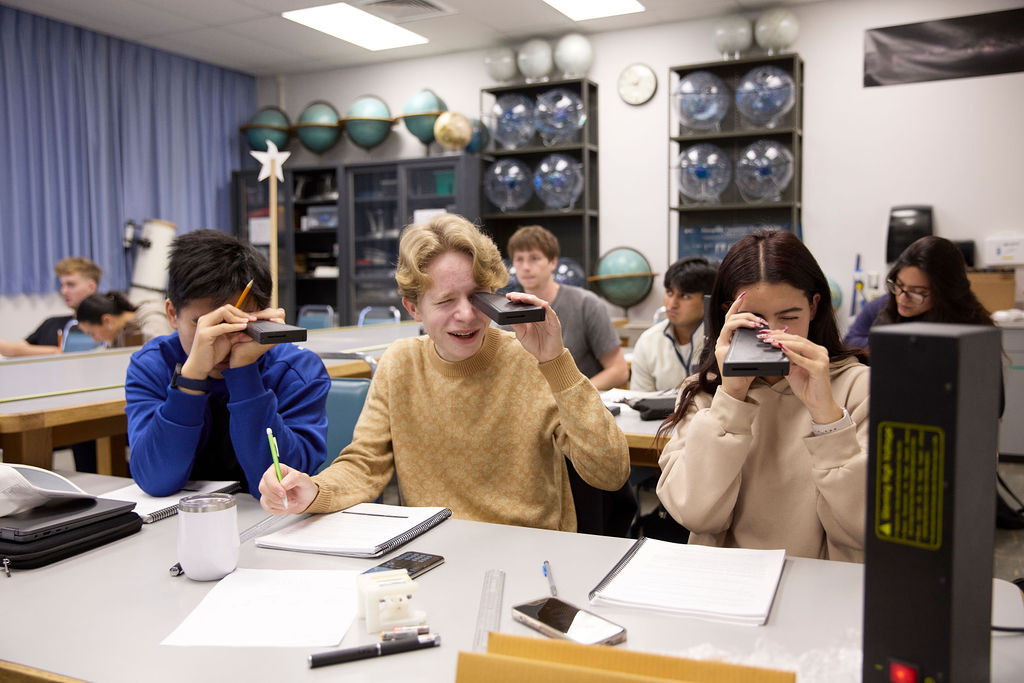 A classroom full of students looking through a lens.