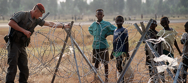 A French soldier, a member of the international force supporting refugees of the Rwandan genocide, adjusts the concertina wire surrounding the airport.