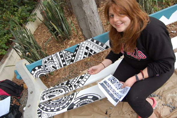 A student paints her design on one of the 19 benches chosen for beautification.