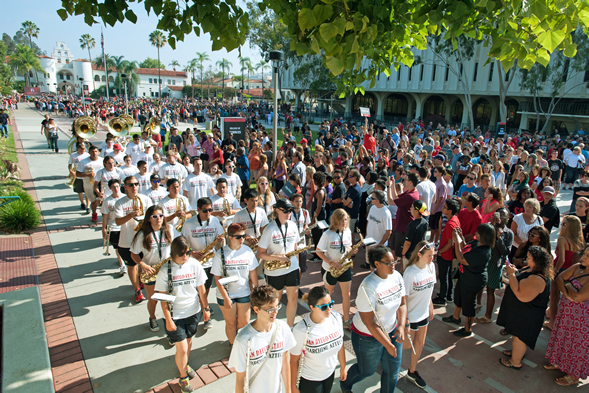The Marching Aztecs and cheerleaders lead the Band Run through campus.