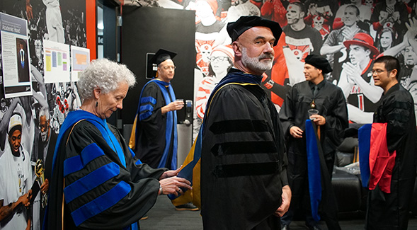 Biology Professor Annalisa Berta provides finishing touches to colleague Roland Wolkowiczs regalia. Photo: Jason Ritchie.