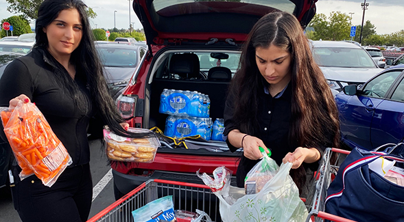 Loading groceries in their car for homebound community members are Milano Sliwa (left), and her sister Monica Sliwa (right).