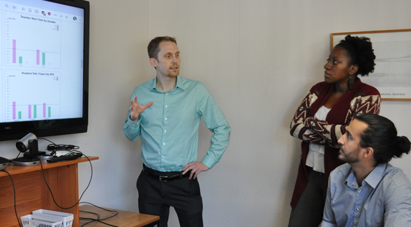 Daniel Reinholz demonstrates an app he developed to evaluate classroom equity to his students Amelia Stone and Antonio Martinez.