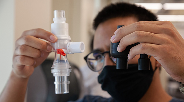 Ener Arvizu-Muoz with a ventilator exhalation valve he designed. Arvizu-Muoz is a part of engineering professor Kevin Wood's lab, which has been working to build a low-cost ventilator.