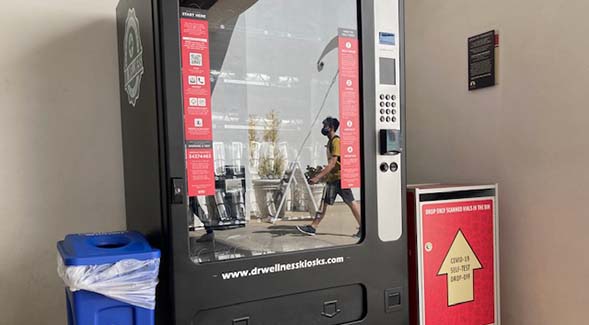 A student was reflected in the glass of a Dr. Wellness COVID-19 test kit kiosk at Conrad Prebys Aztec Student Union. (Photo: Jeff Ristine)