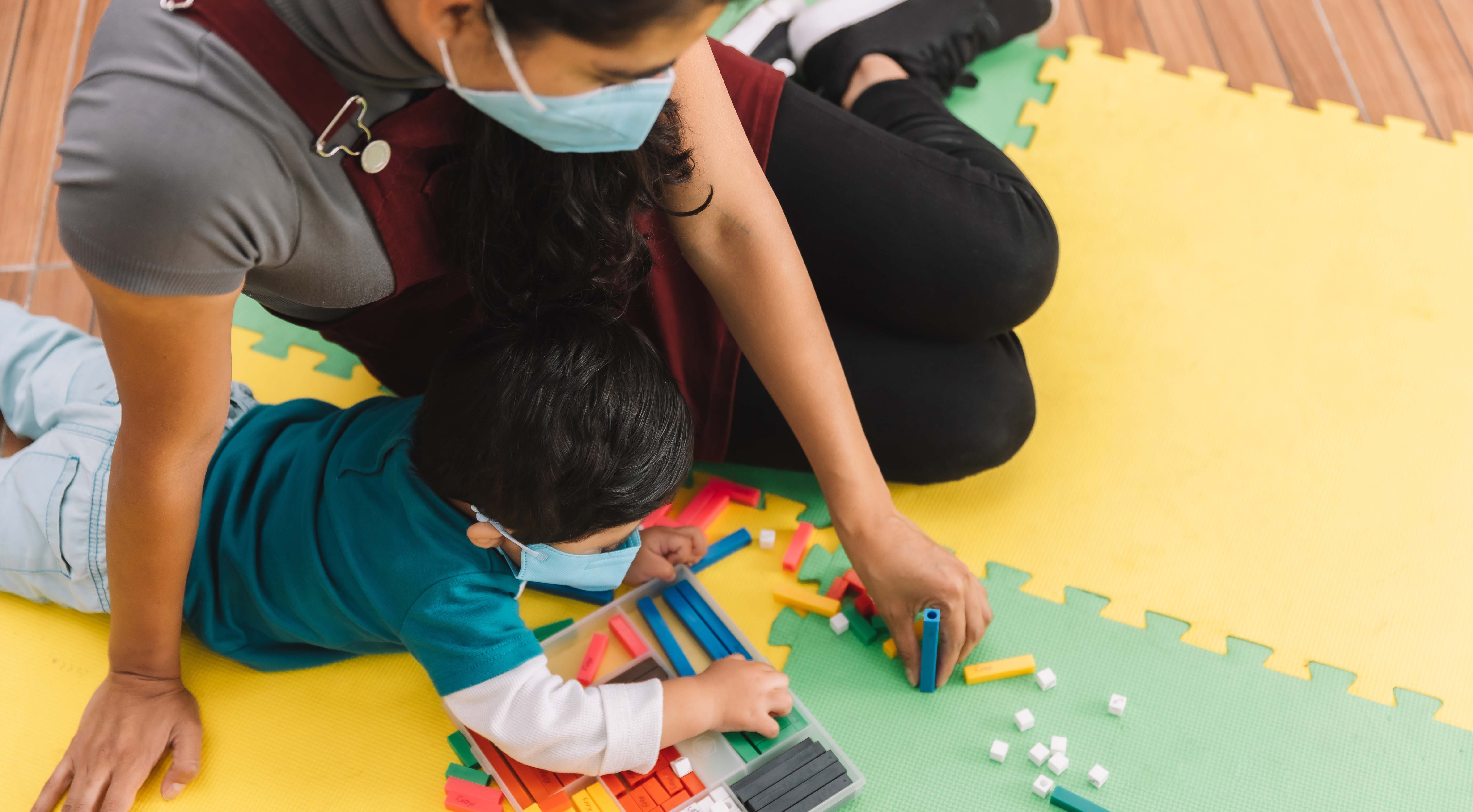 SDSUs Center for Excellence in Early Development is expanding a family child care support program into El Cajon. Above, a teacher plays on the floor with a preschool boy.