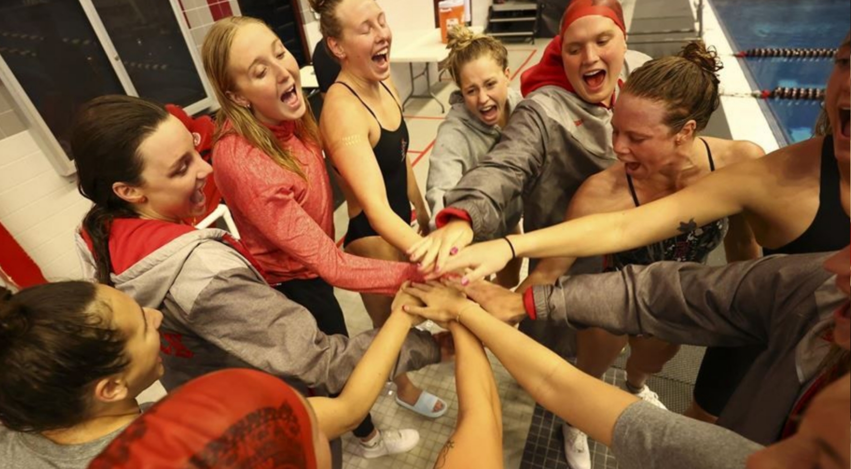 The SDSU Women's Swimming and Diving team gathers poolside during their conference championship.