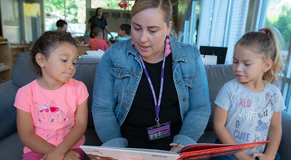 Child and Family Development master's student Flor Burciaga read a book at the SDSU Children's Center. (August 2019 photo)