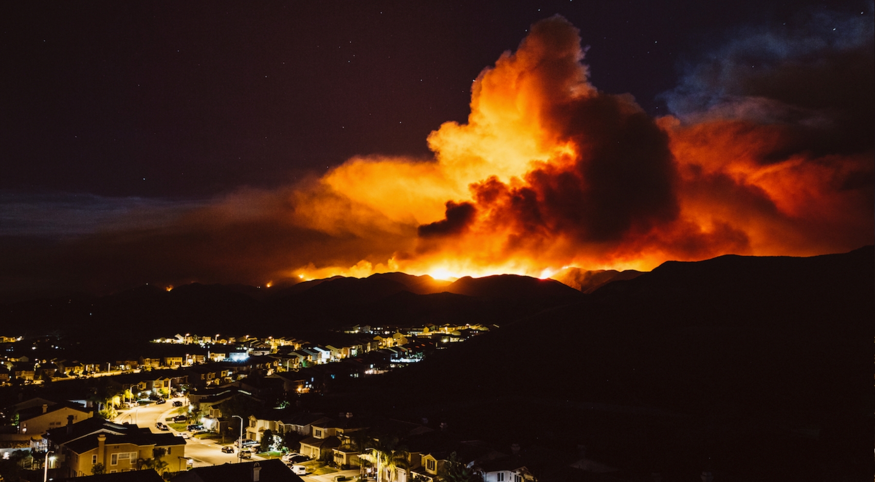 A California wildfire burns near a residential area at night. (Attila Adam/Adobe Stock)