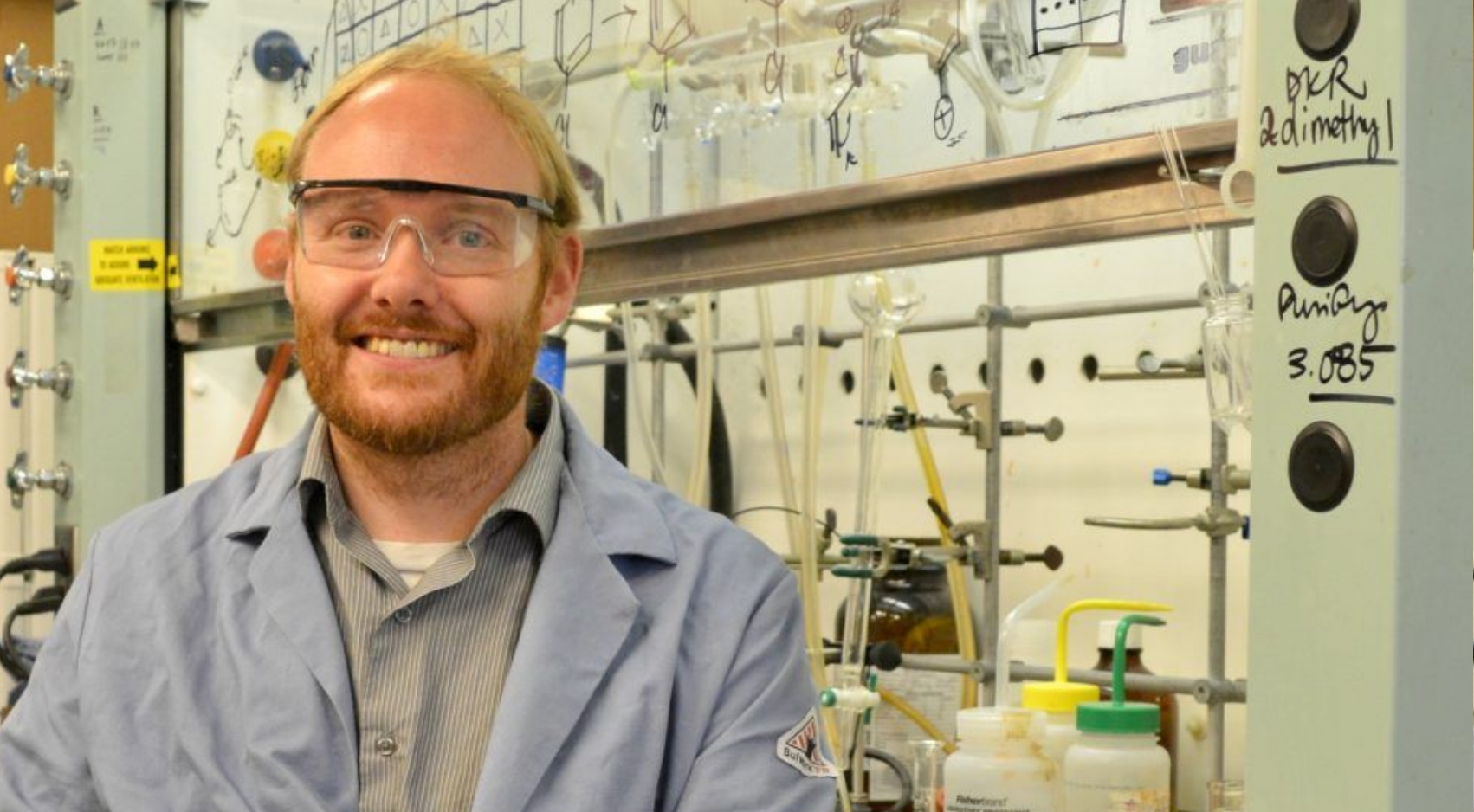 SDSU chemical biologist Jeffrey Gustafson diagrams one of the chemicals he works with on a fume hood