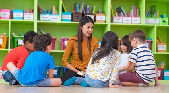 A teacher sat with her students in an elementary school classroom. (Photo: Adobe Stock)