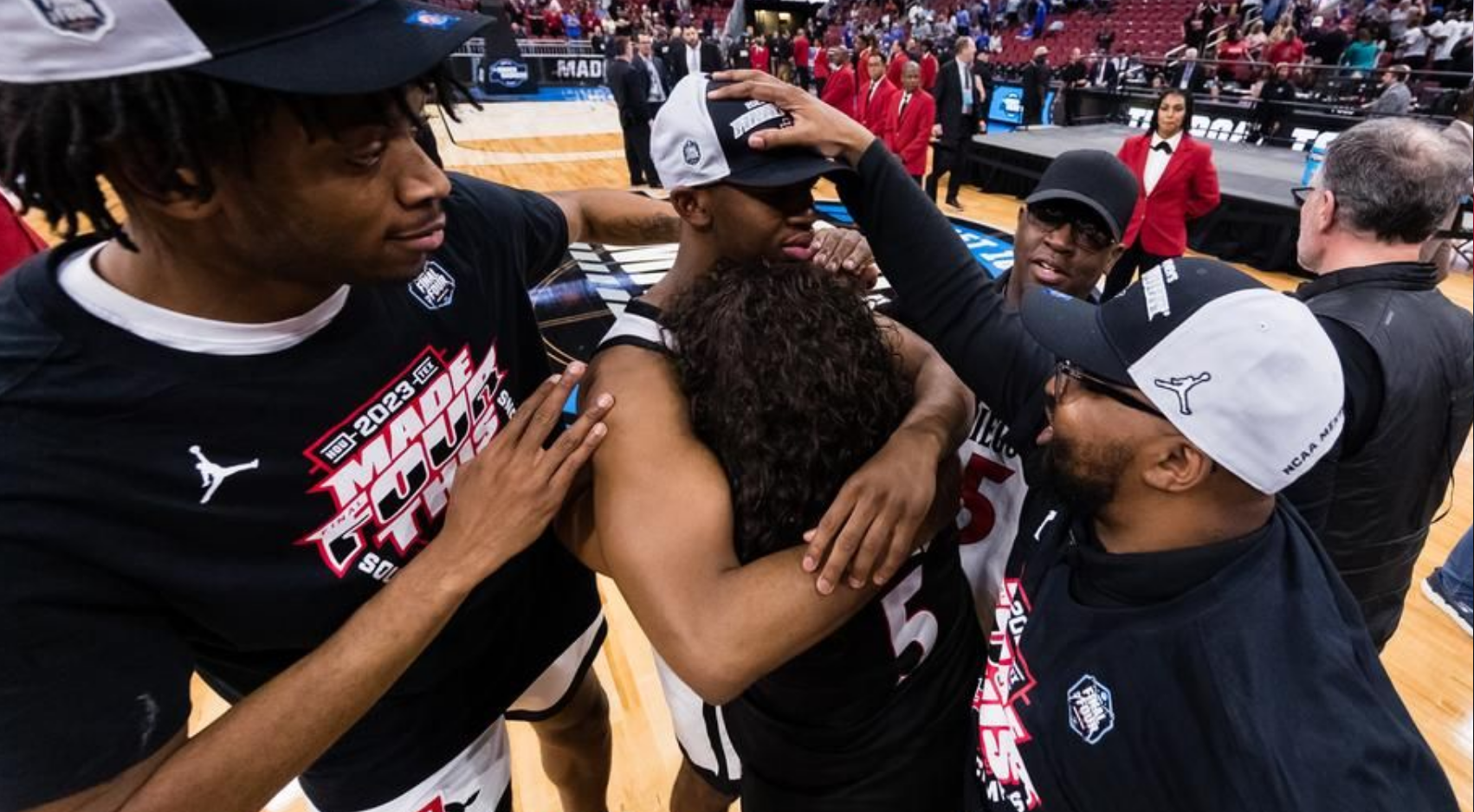 Lamont Butler Jr. hugs his mother, Carmicha Butler, while surrounded by teammate Demarshay Johnson Jr. (left), his father, Lamont Butler Sr. (top), and SDSU coach JayDee Luster (lower right). (SDSU)