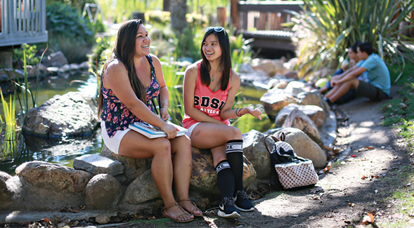 Two students sit at SDSU's turtle pond at Scripps Cottage. (SDSU)