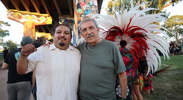 Jose Olague (left) posed at his Chicano Park mural (center column) with professor emeritus Alberto Ochoa. (Photo: Sarah Wilkins)