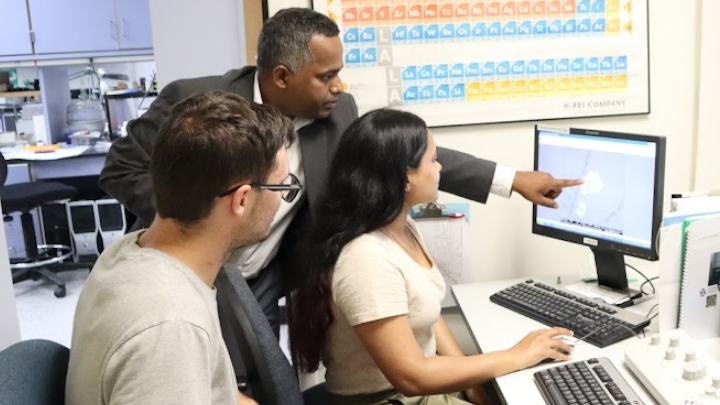 Sanjay Behura (middle) in the Electron Microscopy Facility pointing to a crystal of two-dimensional material exposed to electron beam irradiation. (Bryana Quintana/SDSU)