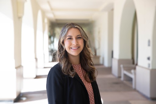 Sandy Mekany, smiling, posed for a portrait under the Student Services West Building