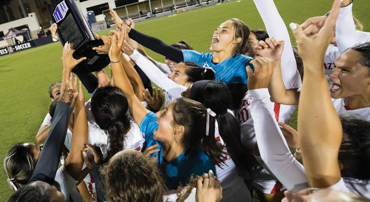 Womens soccer team holds up a trophy