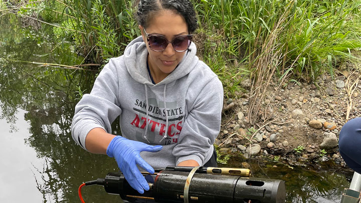Water Innovation and Reuse Lab postdoc Kenisha Shipley deploys a submersible sensor to monitor water quality in Alvarado Creek, a San Diego River tributary. (Photo courtesy of Natalie Mladenov)