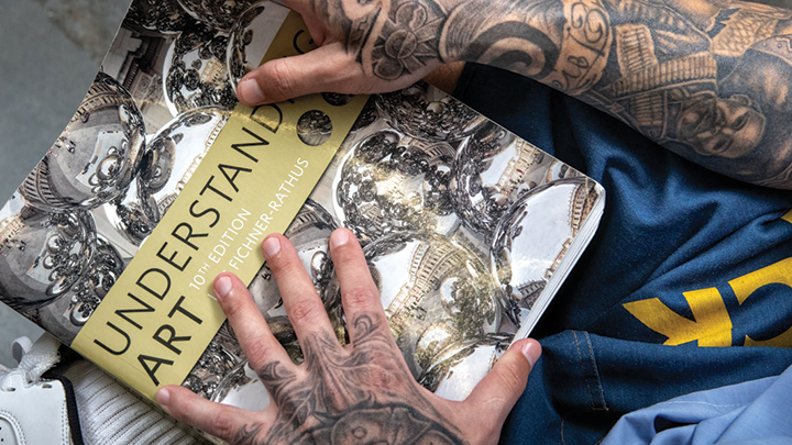 A PAC art student with a textbook at Calipatria State Prison. (Photo by Peter Merts)