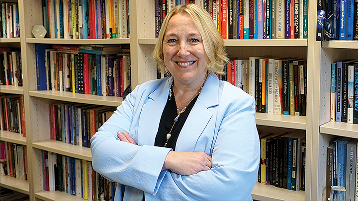 Monica Casper, chair of the Blue Ribbon Task Force on Gender-Based Violence, is photographed in front of a fully stocked bookshelf.