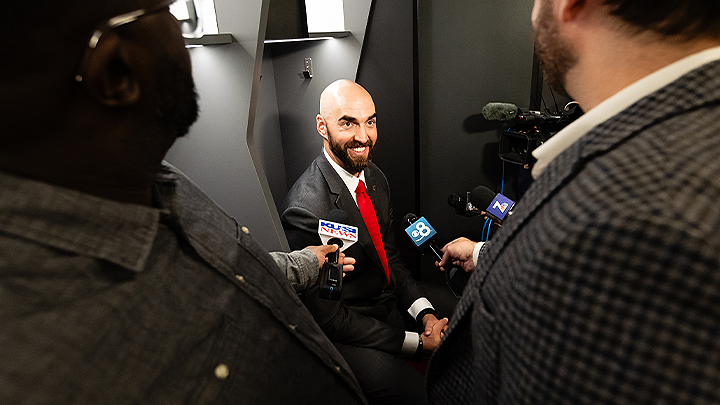 SDSU football coach Sean Lewis surrounded by reporters with cameras and microphones