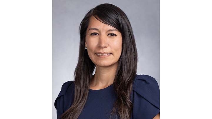 A formal portrait of a woman with long black hair below her shoulders, wearing a dark blue blouse.