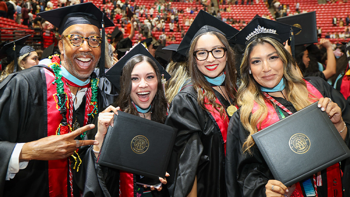 SDSU grads smile for the camera during the 2024 Commencement Ceremonies at Viejas Arena