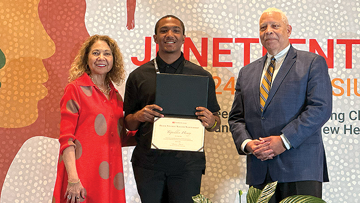 A smiling Tajuddin Henry is photographed holding his certificate.