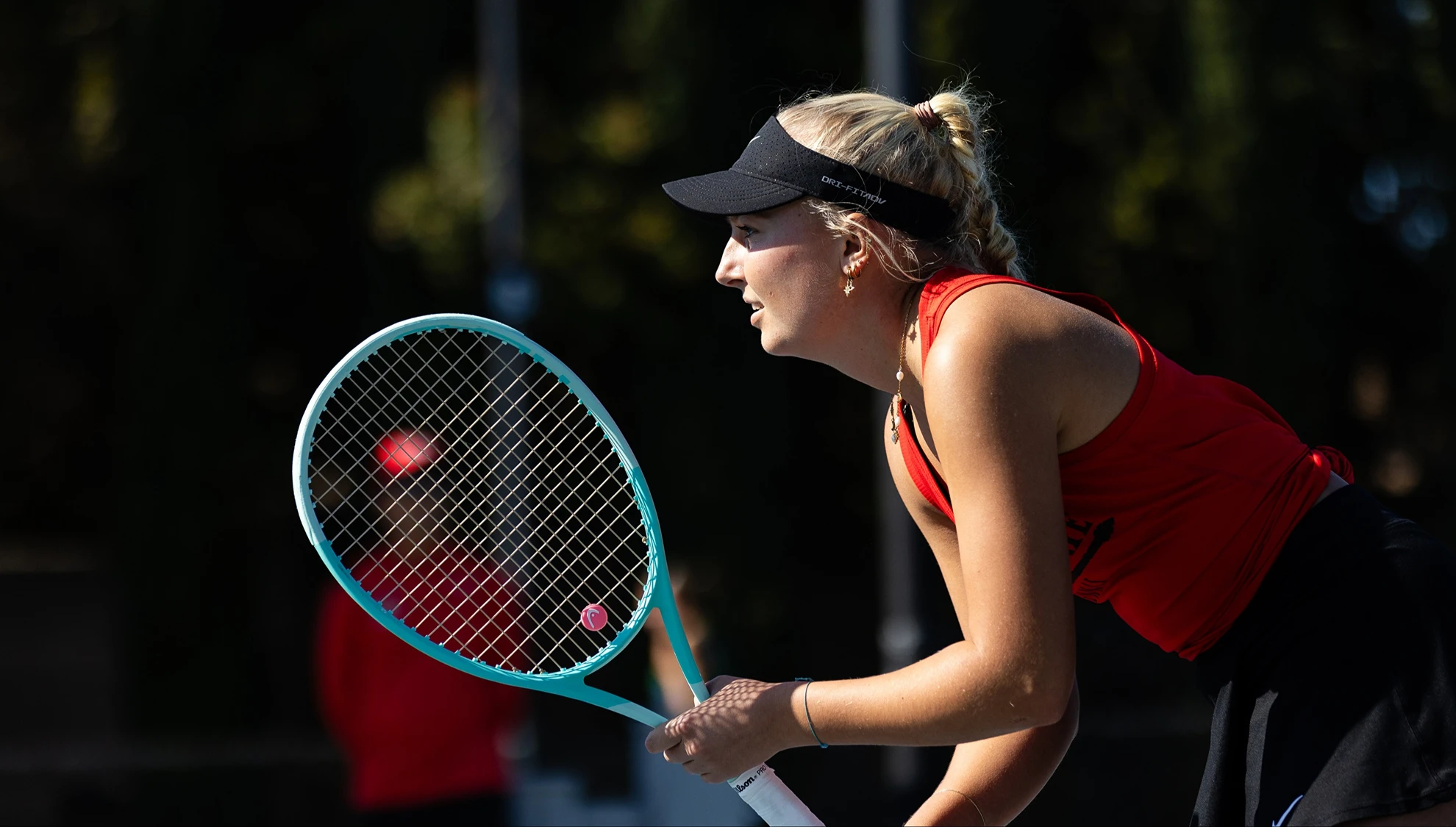 SDSU Women's Tennis player sets up to return a serve during competition
