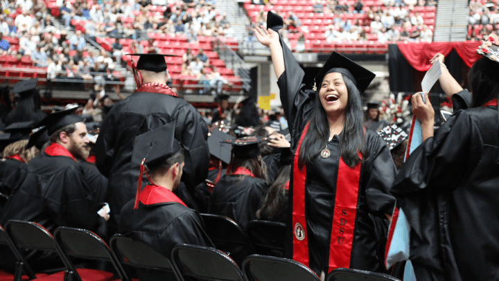 An SDSU graduate waves to their family during commencement ceremonies.