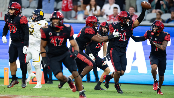 SDSU football players celebrate on field following a play.