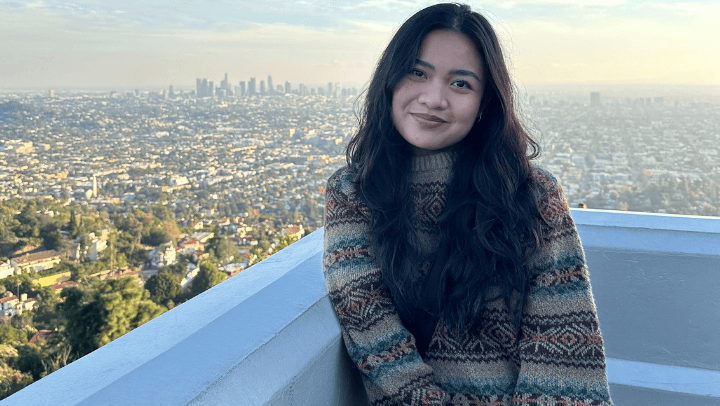 Angelica Castillo poses for a photo with a backdrop of the Los Angeles skyline