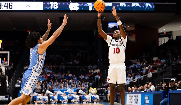 An SDSU basketball player shoots over a defender.
