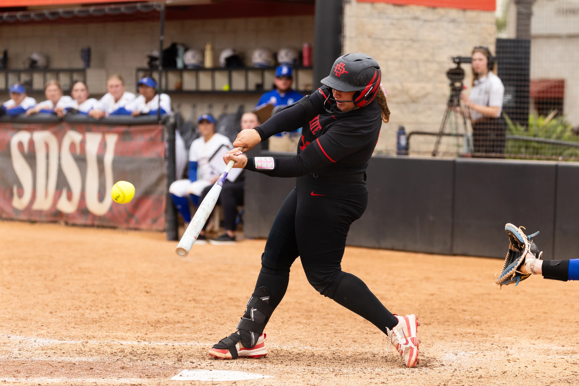 An SDSU softball player swings at a pitch during a game.