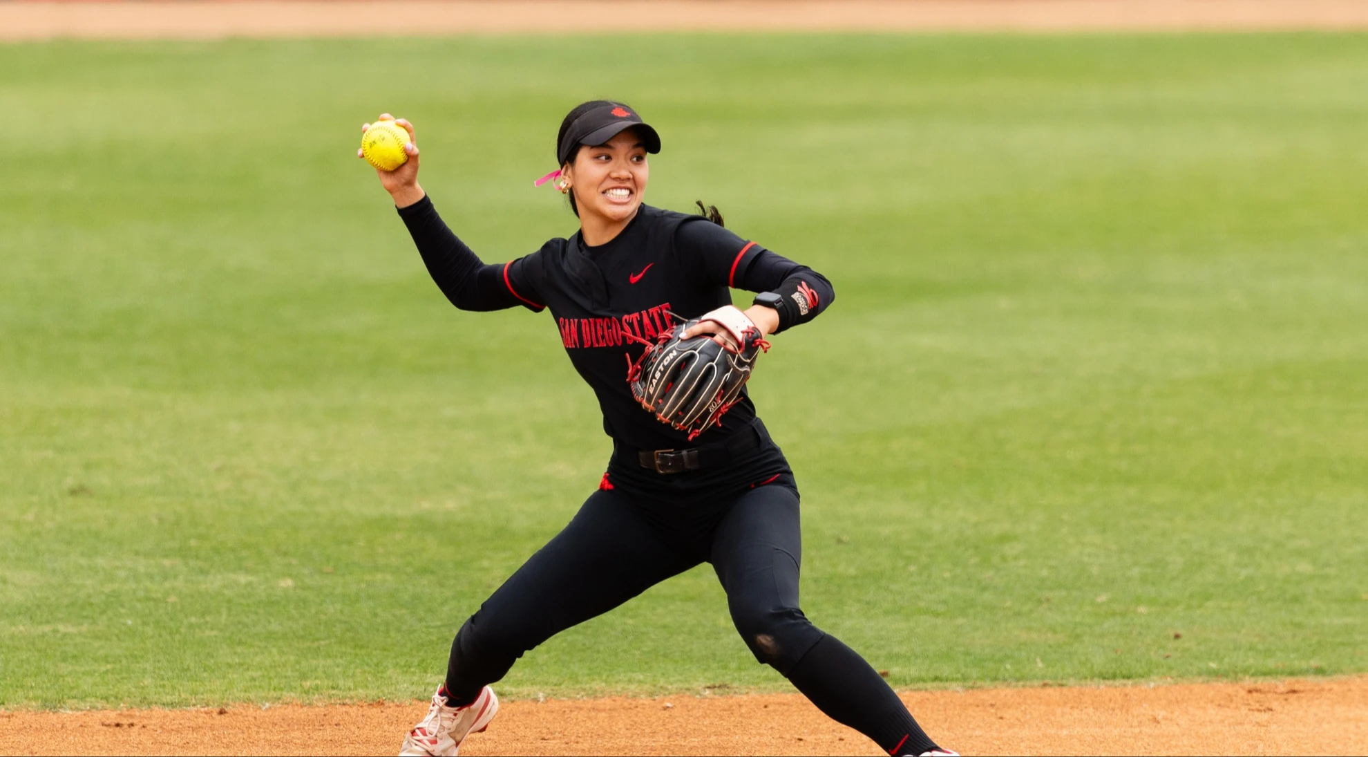 Quinn Waiki dressed in a black SDSU uniform, sets up to throw during a game.