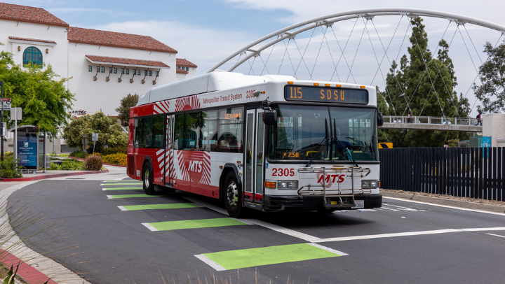 A public transit bus drives past the SDSU campus
