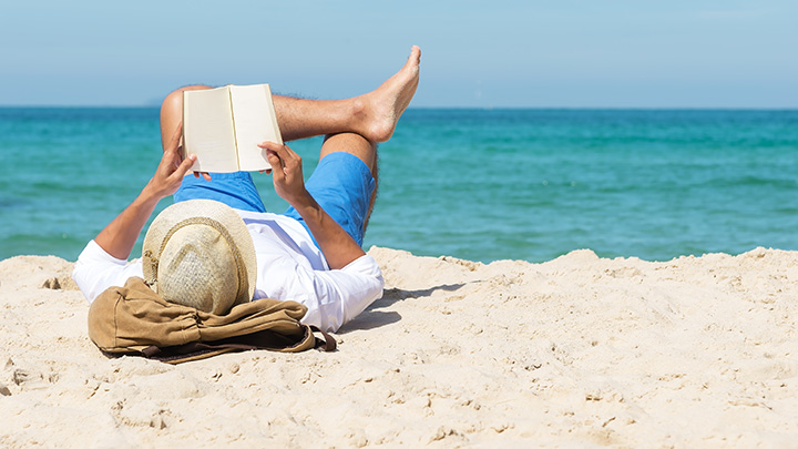 A person reading a book on the beach.