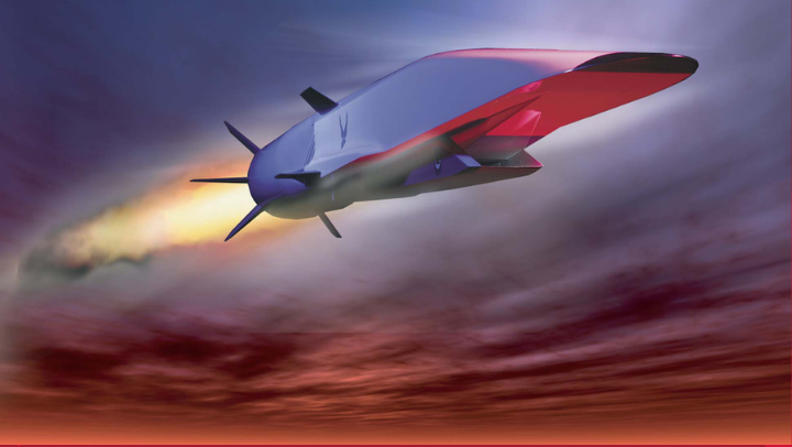 A silvery, futuristic aircraft with a broad, flat nose and no doors, windows or wings is soaring through the air just under the clouds with a jet of fire coming from the rear and its tail fins. 