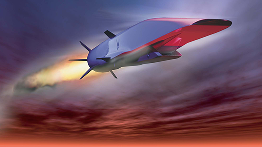 A silvery, futuristic aircraft with a broad, flat nose and no doors, windows or wings is soaring through the air just under the clouds with a jet of fire coming from the rear and its tail fins.