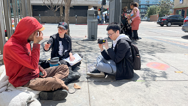 Co-PI Gabriela Fernandez interviews an unhoused community member downtown while student Jiachen Wang records the interaction. (Photo courtesy of Xinyu Du)