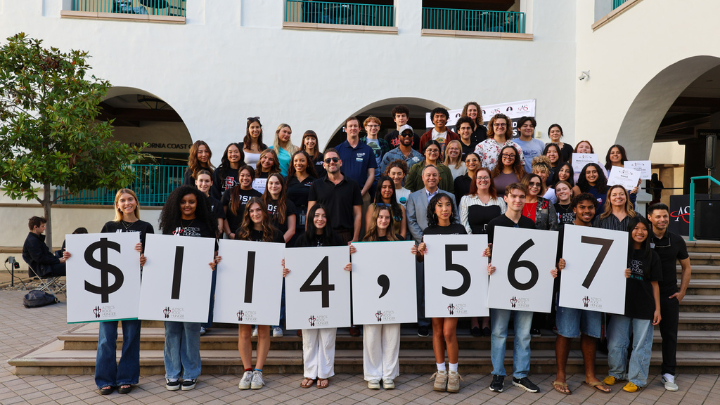 Students holding up signs spelling out the amount of money donated.