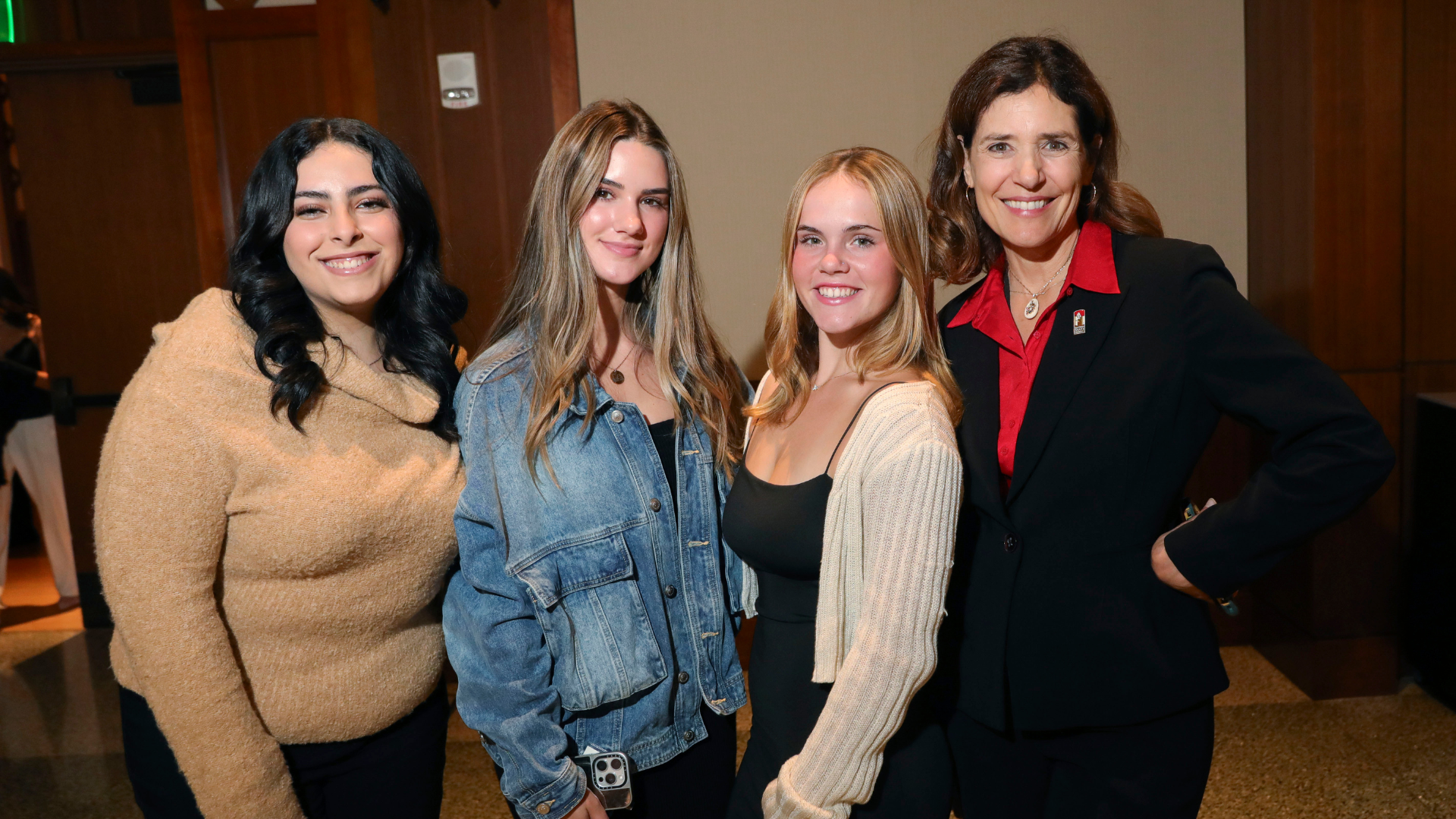 4 people smiling next to each other posing for a photo.