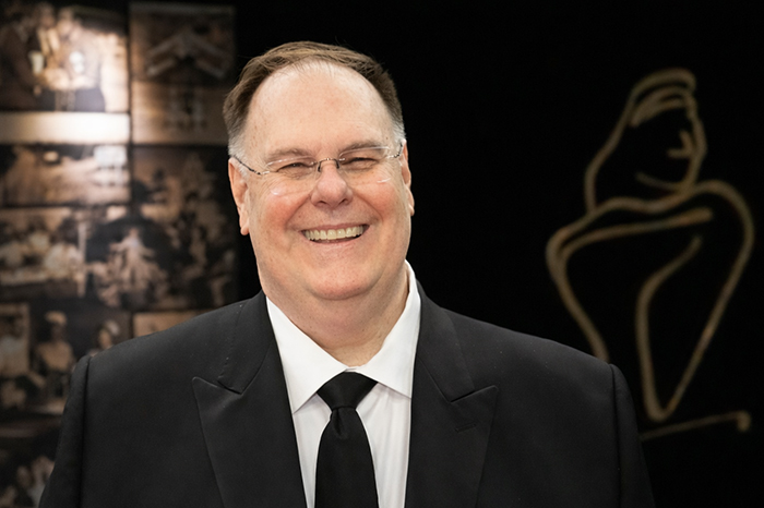 A man smiling in front of a backdrop 