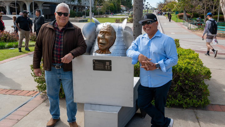 2 men posing beside a statue